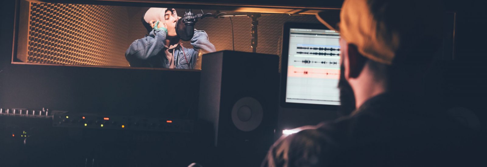 Hipster singer and music producer recording music in professional studio Young music artist and singer performing song and working with music producer in recording studio